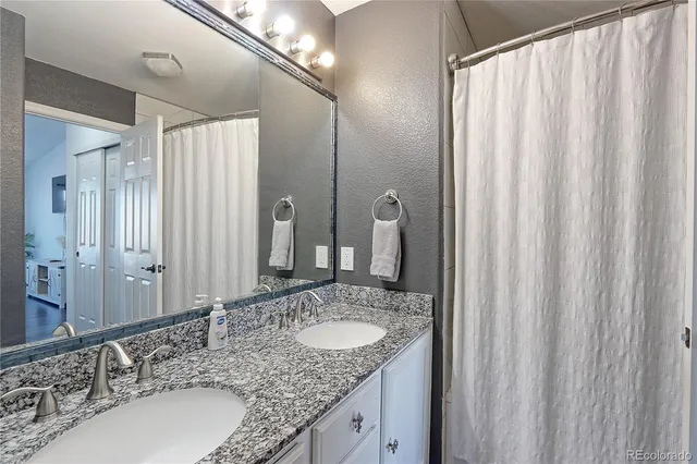 a bathroom with a granite countertop sink and a mirror