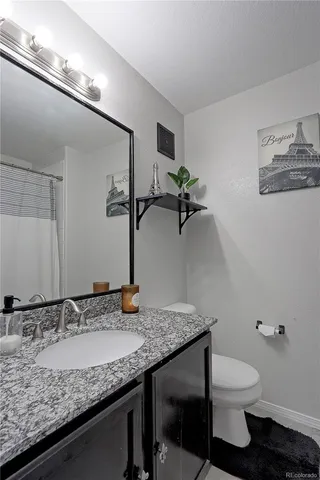 a bathroom with a granite countertop sink a toilet and mirror