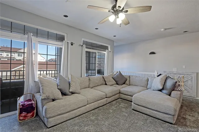 a living room with furniture ceiling fan and a window