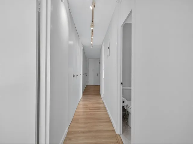 a view of a hallway with wooden floor and staircase
