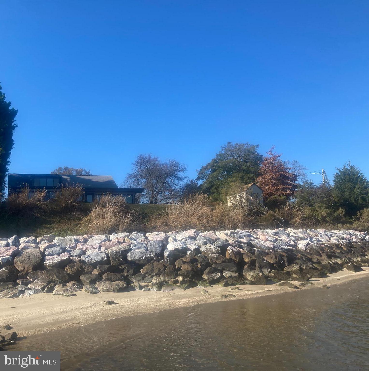 Sandy beach in front of armor stone w/home above