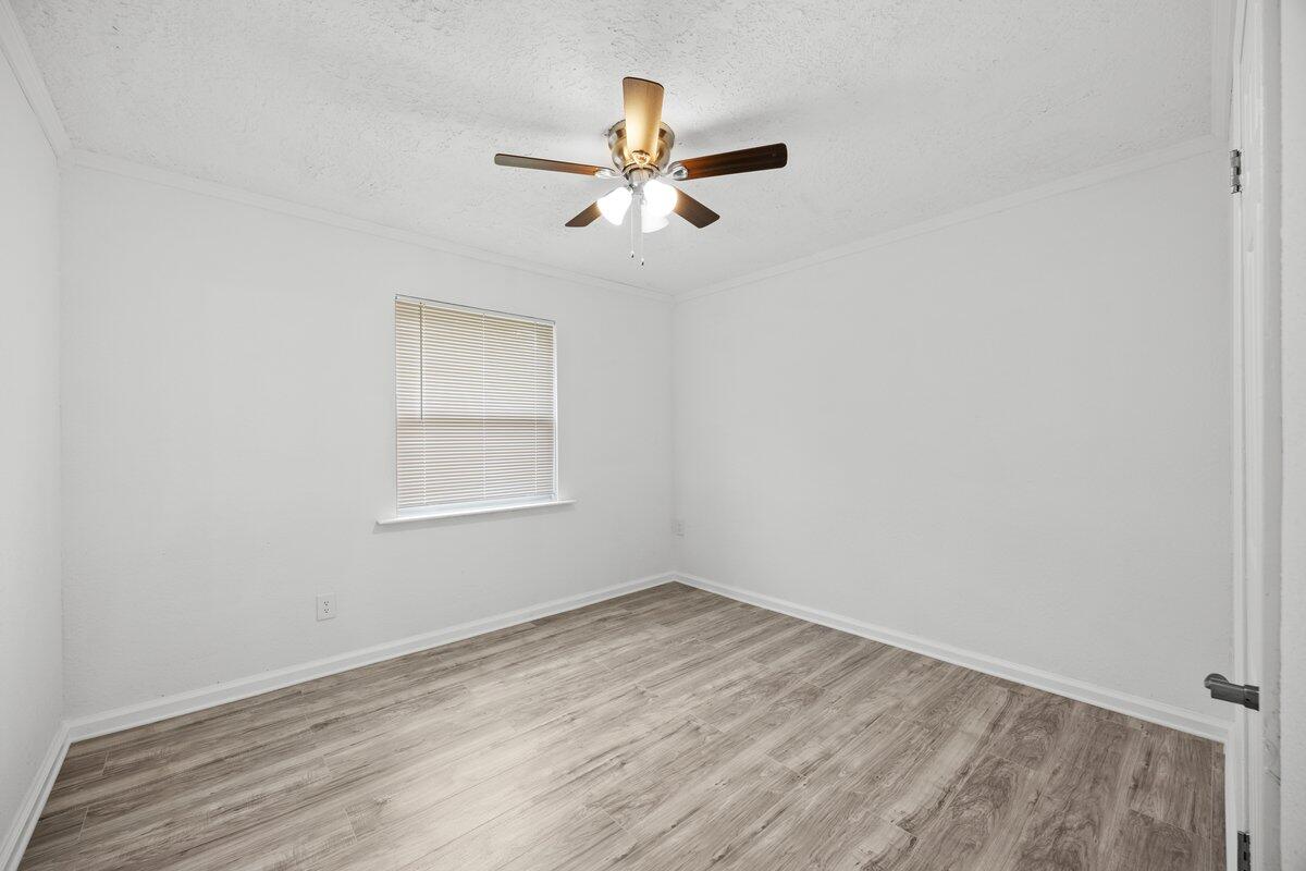 4352 Watkins Street Pace, FL 32571 - Photo 15 of 24 an empty room with wooden floor ceiling fan and window