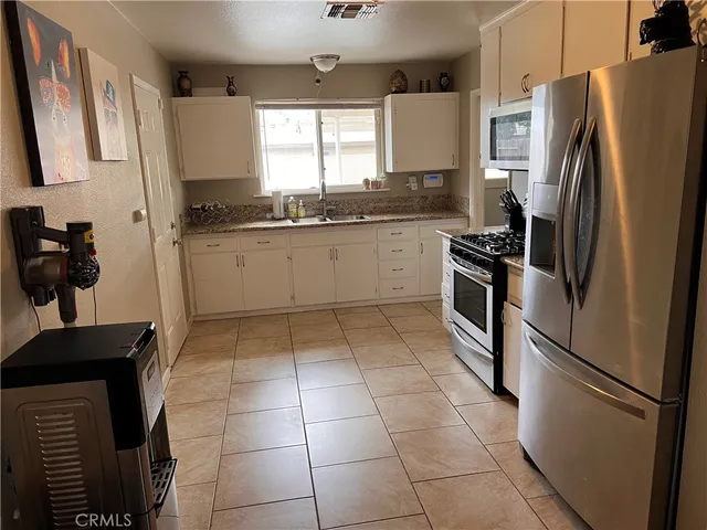 a kitchen with granite countertop a refrigerator and a stove top oven