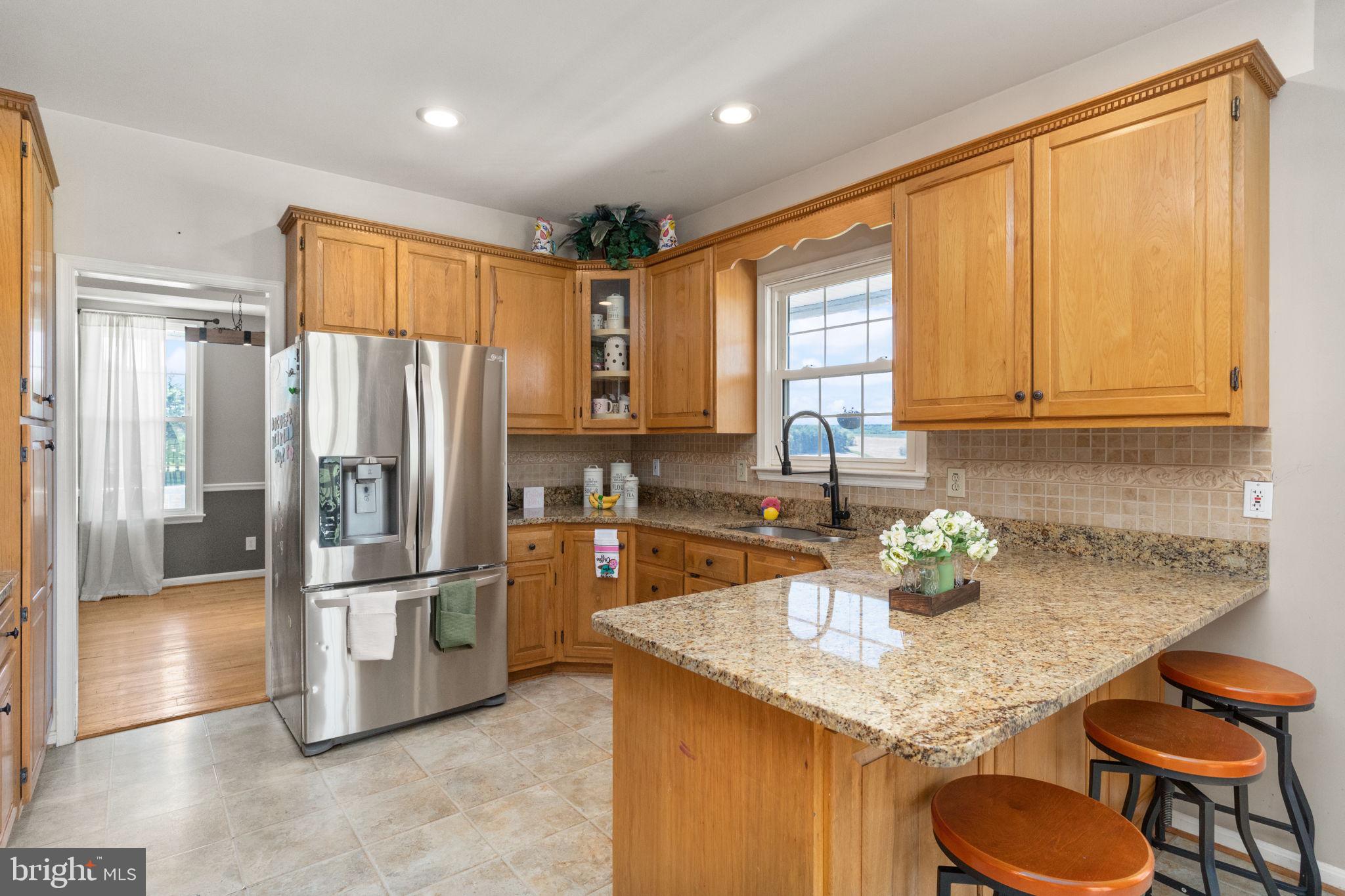 2140 Marston Road New Windsor, MD 21776 - Photo 11 of 48 a kitchen with granite countertop kitchen island stainless steel appliances a refrigerator a sink a stove a table and chairs