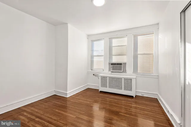a view of an empty room with window and wooden floor