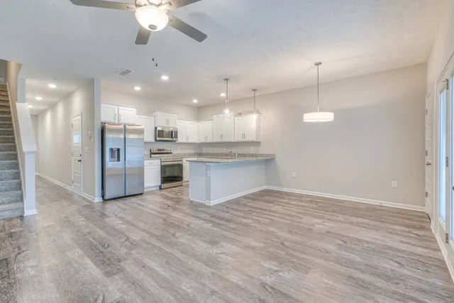 a view of kitchen with refrigerator stove and wooden floor