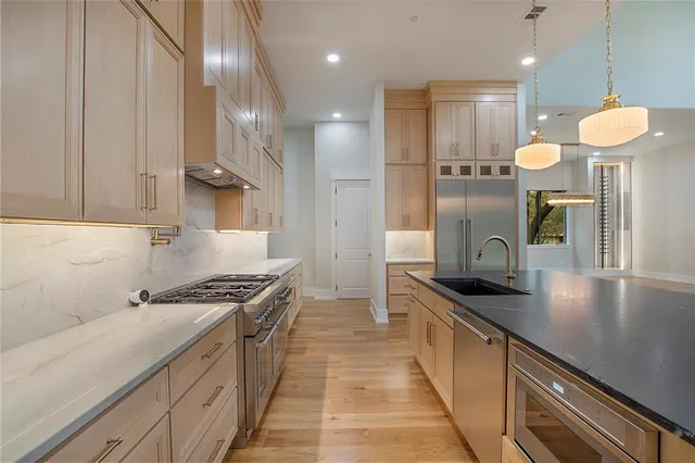 a kitchen with stainless steel appliances granite countertop a sink a stove and a refrigerator