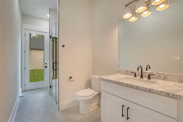 a bathroom with a granite countertop sink a toilet and a mirror