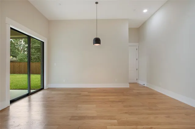 a view of an empty room with wooden floor and windows