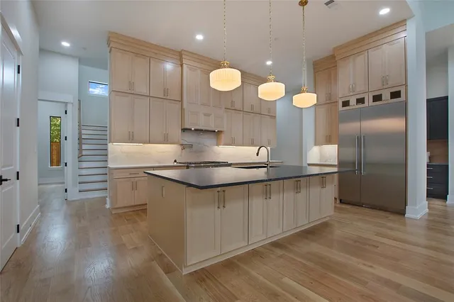 a kitchen with stainless steel appliances granite countertop a sink a stove and a wooden floors