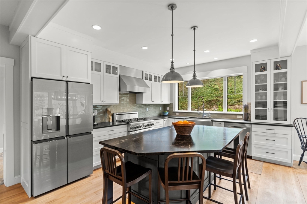 7 Bradlee Road Marblehead, MA 01945 - Photo 5 of 41 a kitchen with stainless steel appliances granite countertop a dining table chairs refrigerator and wooden floor