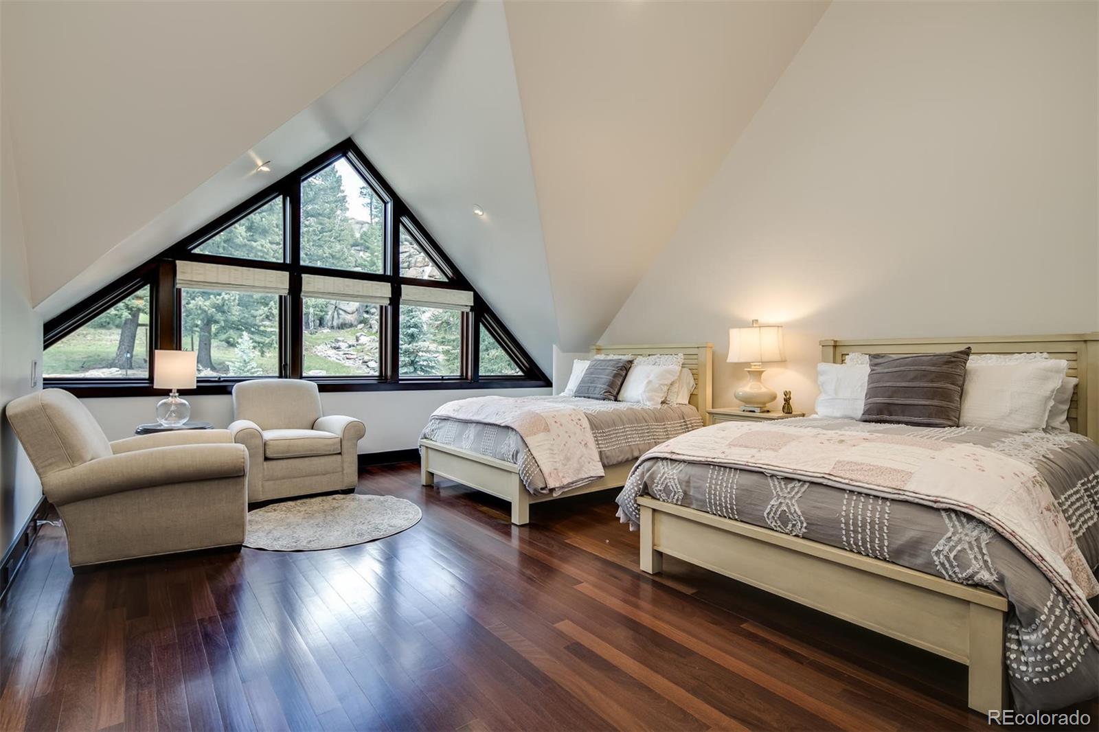 6917 Timbers Drive Evergreen, CO 80439 - Photo 23 of 39 a bedroom with a bed and a couch next to a large window