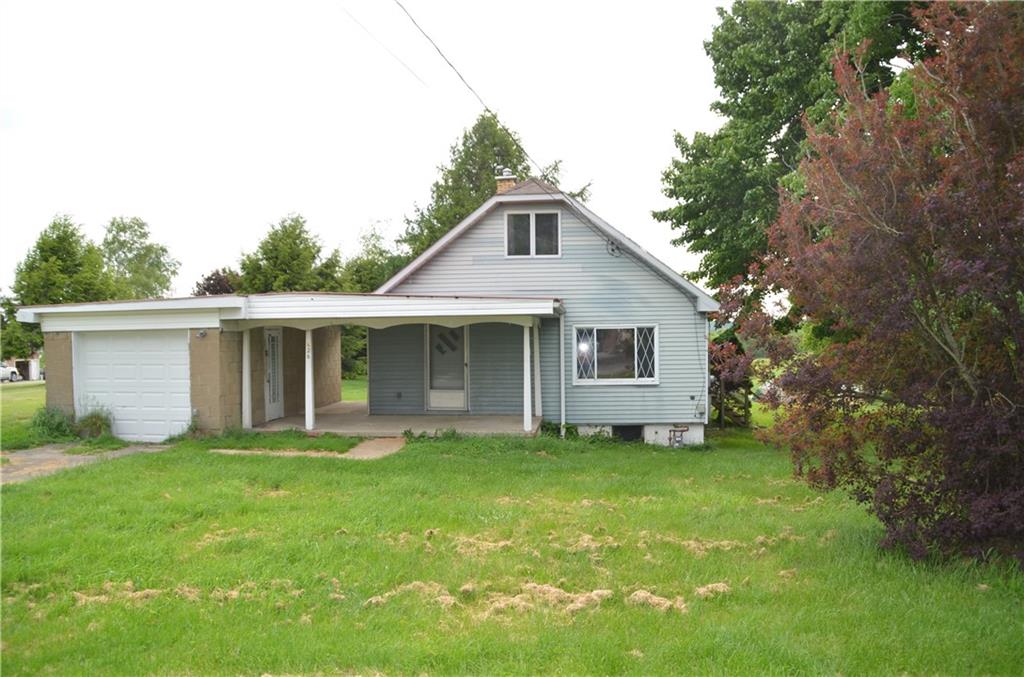 a front view of house with yard and trees in the background