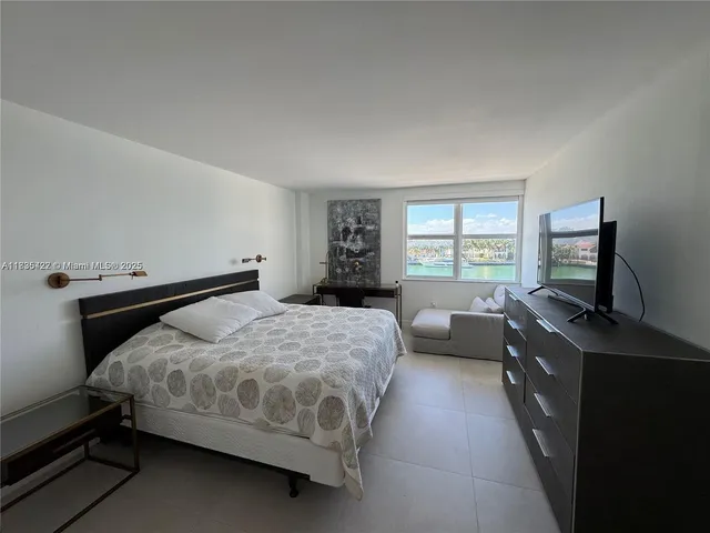 a bedroom with a bed and a flat tv screen on the dresser