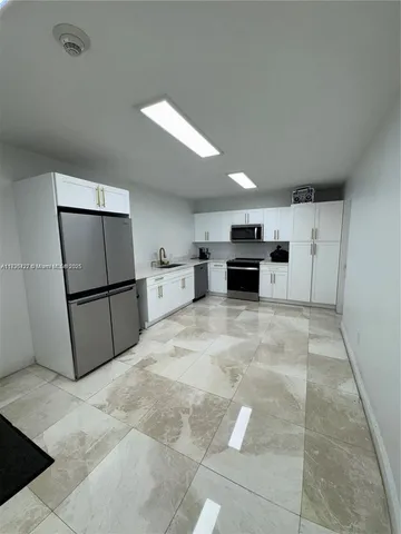a view of a kitchen with furniture and a refrigerator