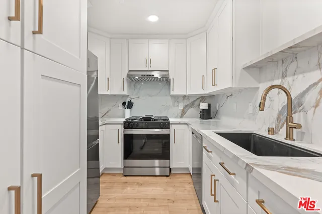 a kitchen with white cabinets stainless steel appliances and sink