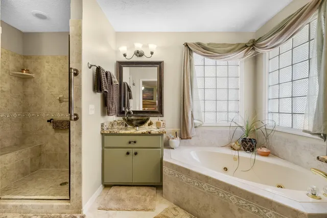 a bathroom with a granite countertop sink mirror and a bathtub