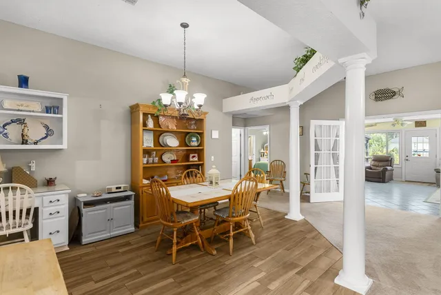 a view of a dining room and livingroom with furniture wooden floor a chandelier