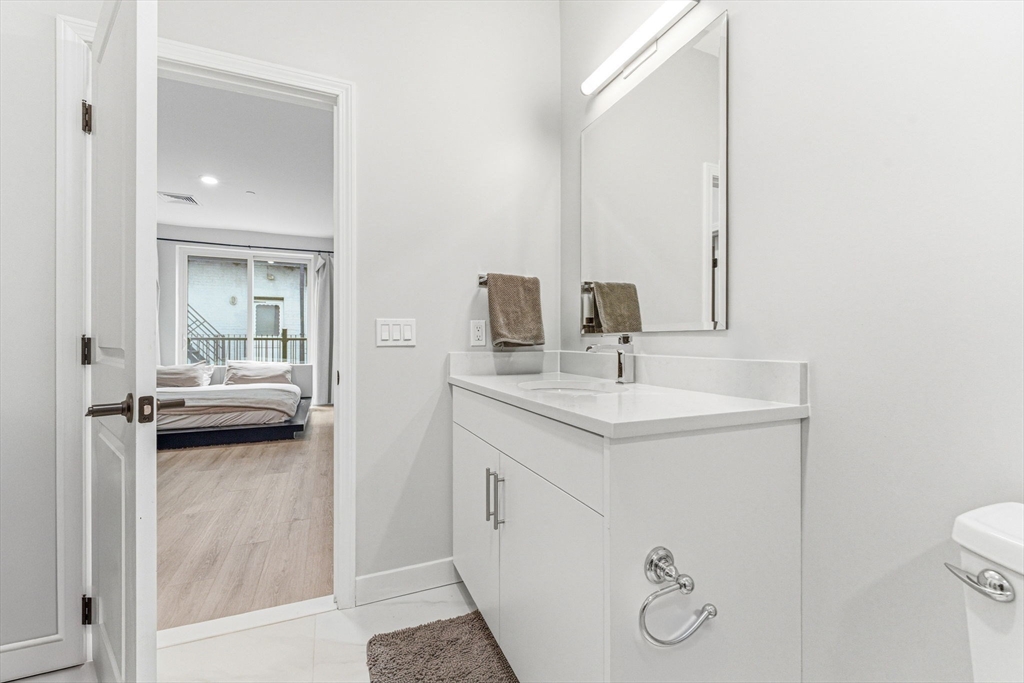 157 Chestnut Street, Unit 203 Chelsea, MA 02150 - Photo 17 of 31 a en suite bathroom with a granite countertop sink and a mirror
