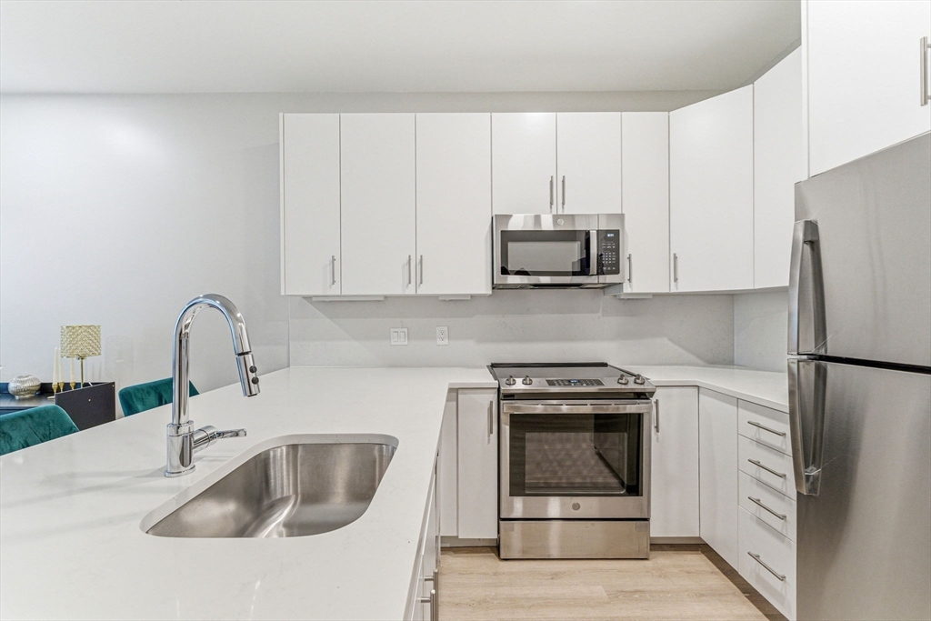 157 Chestnut Street, Unit 203 Chelsea, MA 02150 - Photo 3 of 31 a kitchen with granite countertop a stove a sink and a microwave
