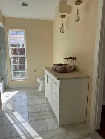 a bathroom with a granite countertop sink a toilet and a shower