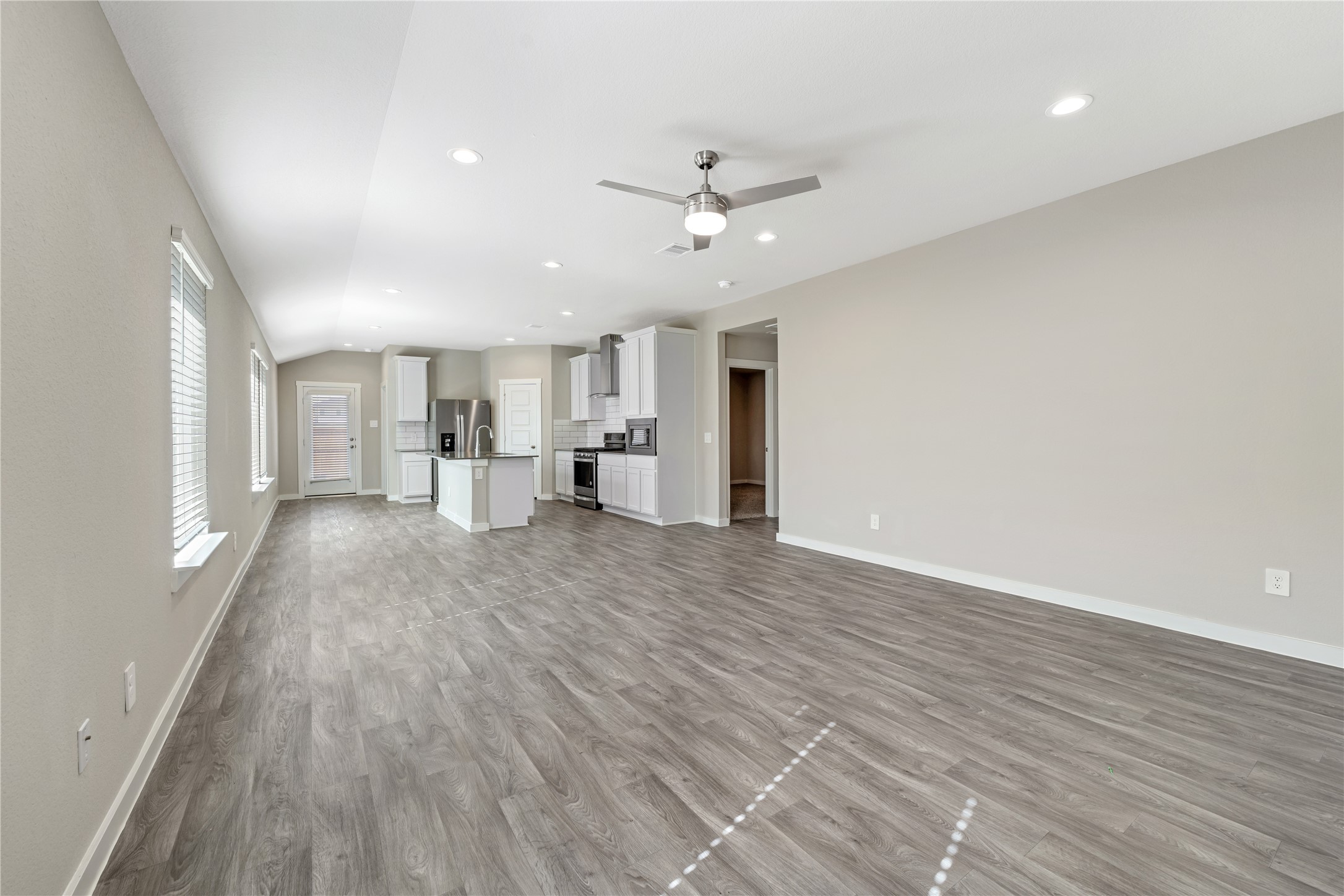 12722 Basinghall Lane Houston, TX 77047 - Photo 5 of 22 a view of a big room with wooden floor a ceiling fan and windows