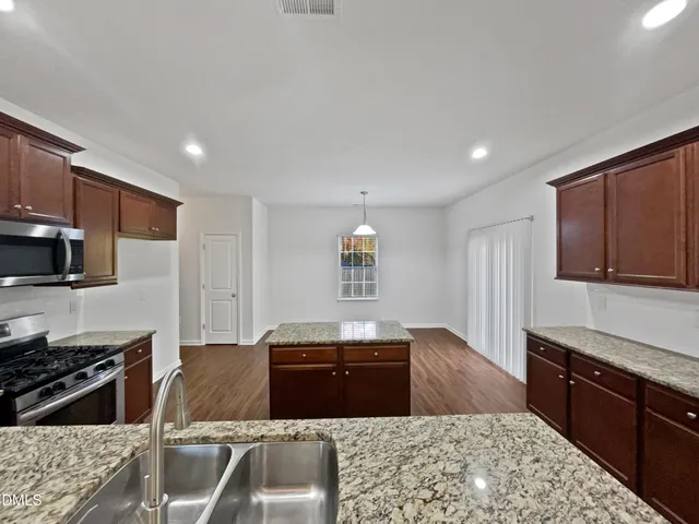 a kitchen with stainless steel appliances granite countertop a stove a sink and a microwave