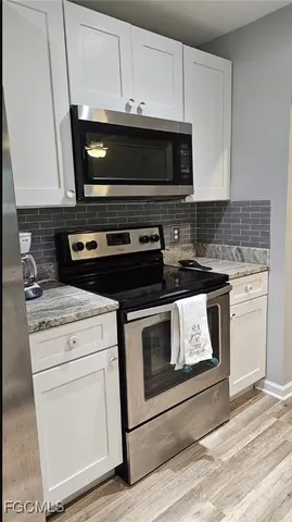 a stove top oven sitting inside of a kitchen with stainless steel appliances wooden floor and cabinets