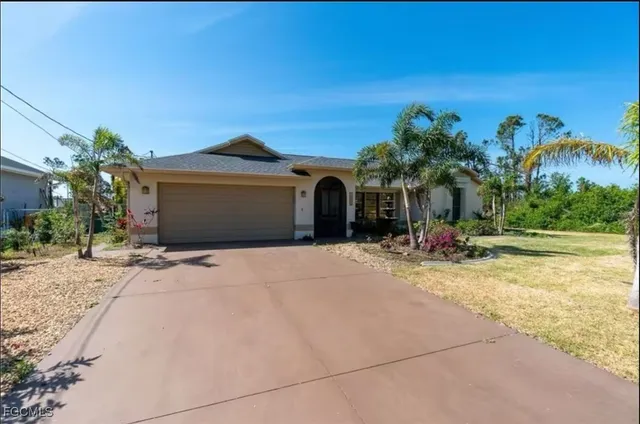 a view of a house with a yard and palm trees