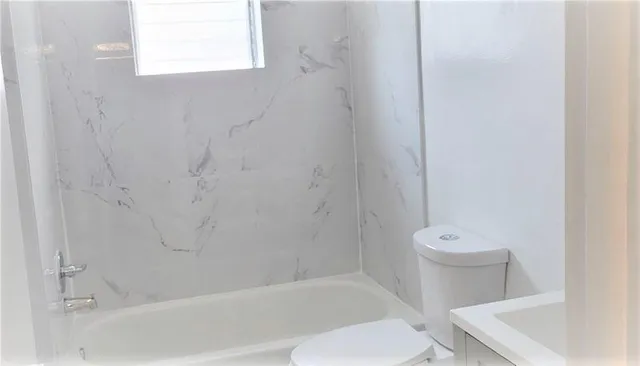 a white toilet sitting next to a bath tub