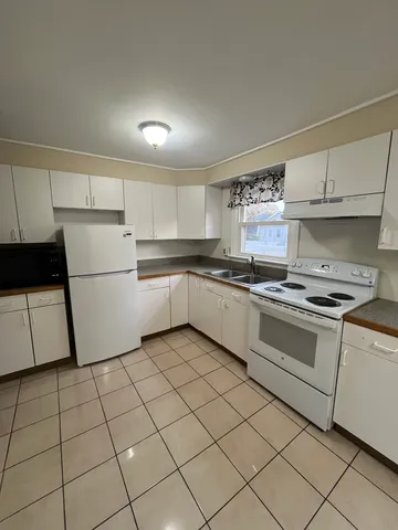a kitchen with white cabinets a sink and white appliances