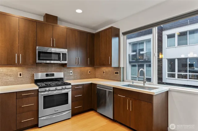 a kitchen with stainless steel appliances granite countertop a stove a sink and a microwave