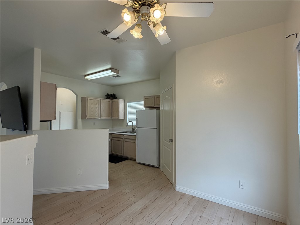 5525 West Flamingo Road, Unit 2016 Las Vegas, NV 89103 - Photo 11 of 20 Kitchen with arched walkways, freestanding refrigerator, a ceiling fan, light countertops, and light wood finished floors