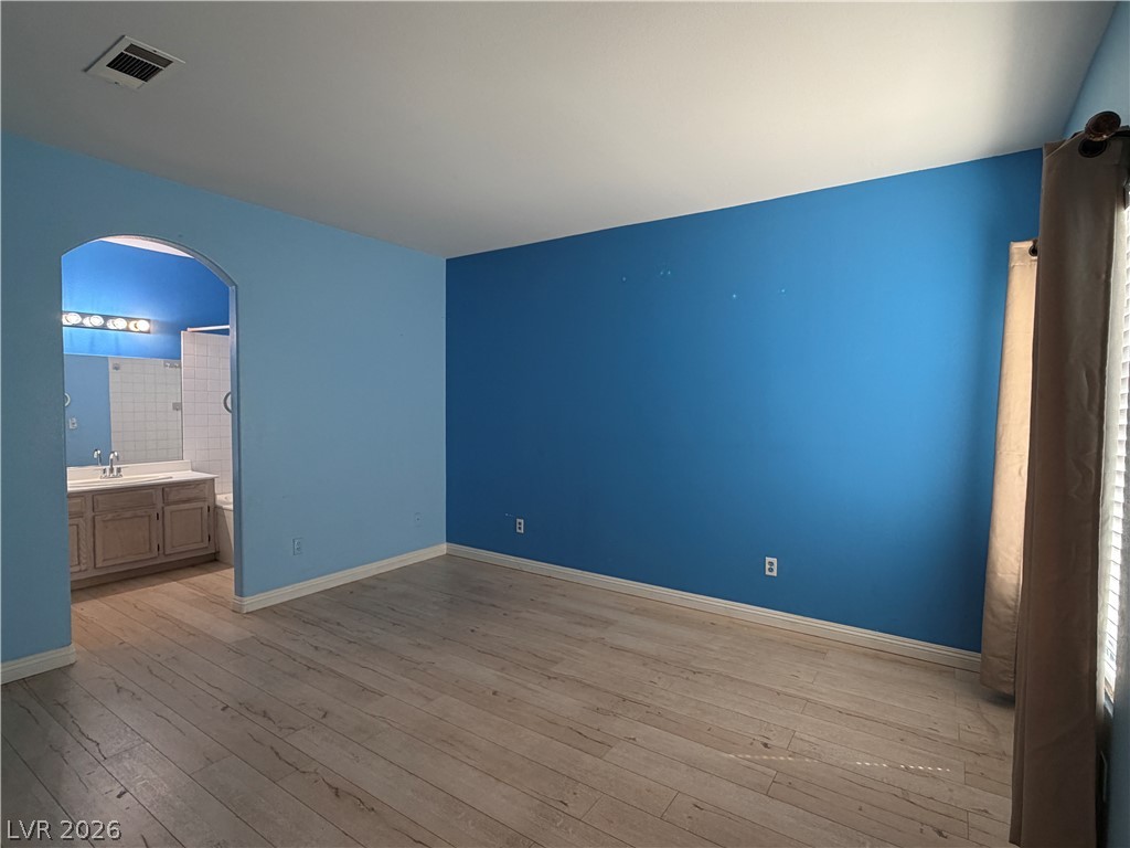 5525 West Flamingo Road, Unit 2016 Las Vegas, NV 89103 - Photo 14 of 20 Unfurnished bedroom featuring arched walkways, light wood-style floors, and ensuite bath