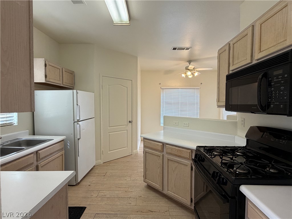 5525 West Flamingo Road, Unit 2016 Las Vegas, NV 89103 - Photo 5 of 20 Kitchen with black appliances, light countertops, light wood finish cabinets, a peninsula, and light wood-type flooring