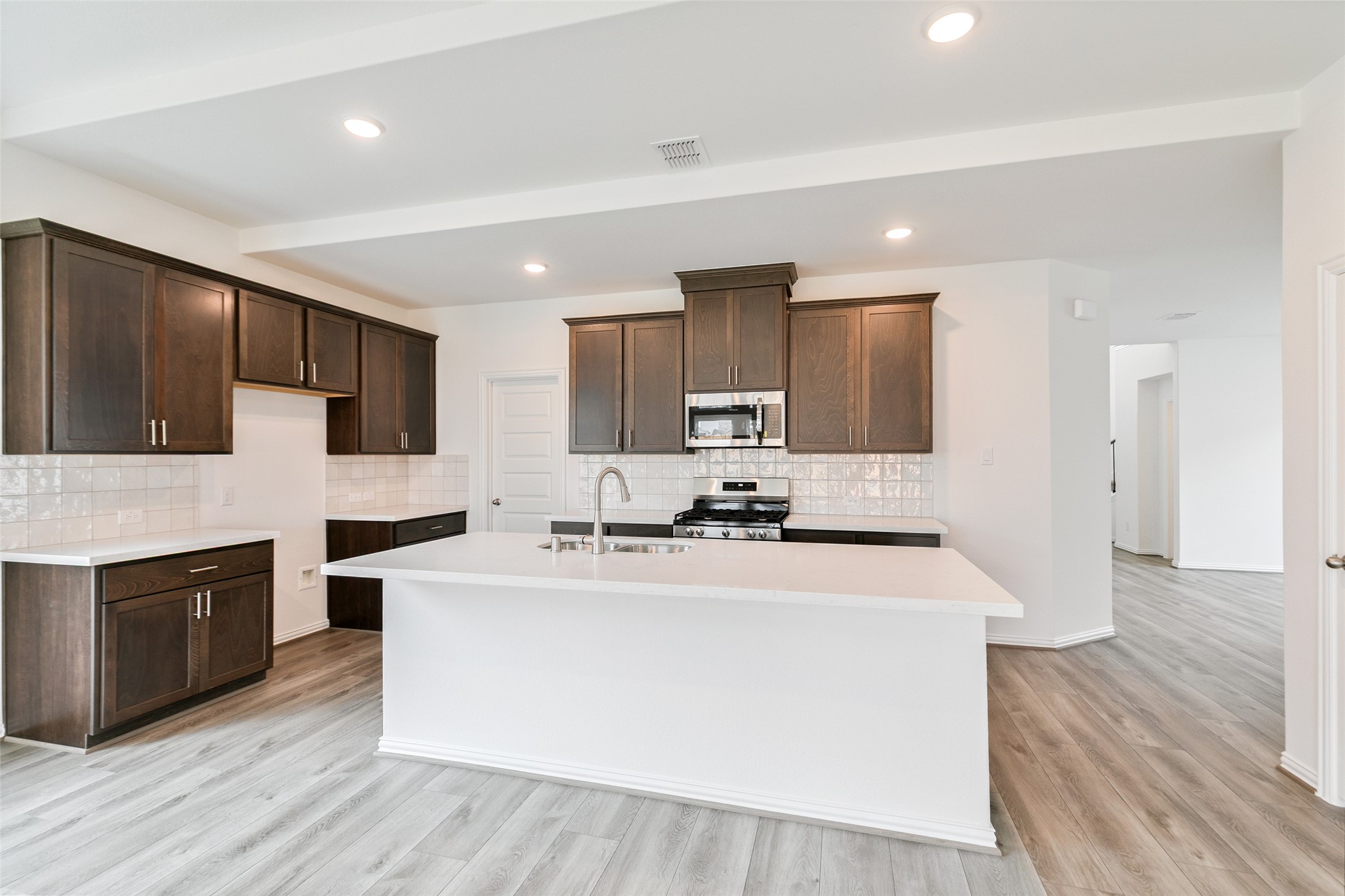 2710 Alexis Street Seabrook, TX 77586 - Photo 14 of 46 a white kitchen with wooden floor and stainless steel appliances