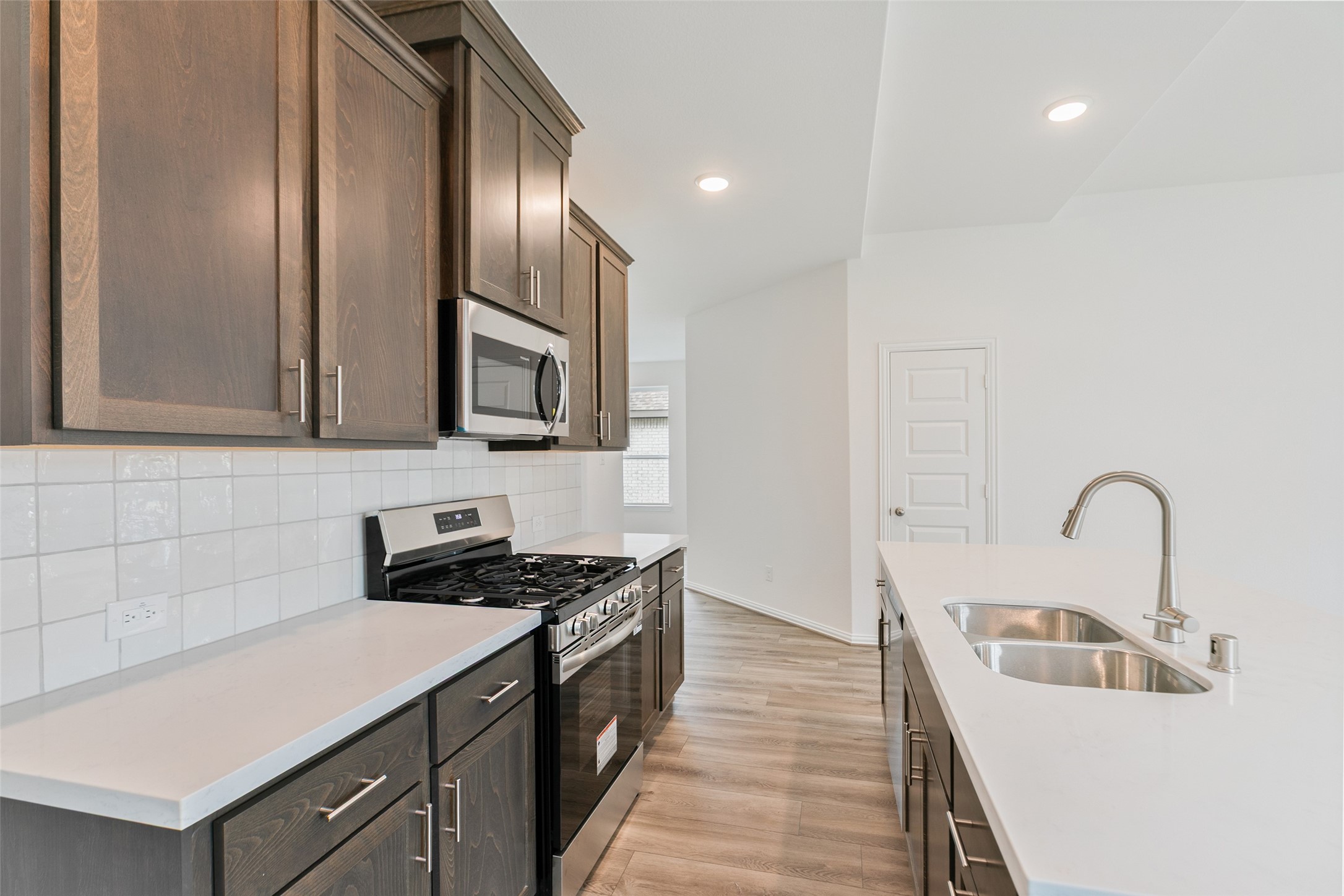 2710 Alexis Street Seabrook, TX 77586 - Photo 17 of 46 a kitchen with stainless steel appliances a sink a stove and a refrigerator with wooden floor