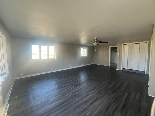 an empty room with wooden floor and windows