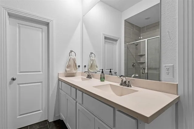 a bathroom with a double vanity sink mirror and shower