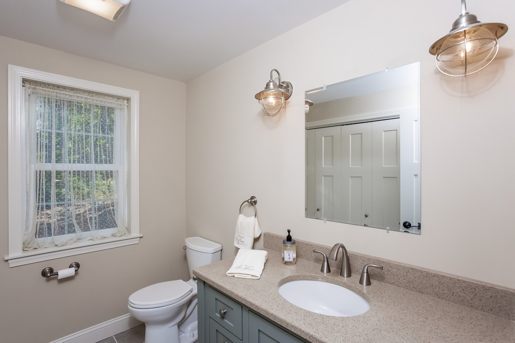 321 Cap'n Lijah's Road Barnstable, MA 02632 - Photo 6 of 10 a bathroom with a granite countertop toilet a sink and a mirror