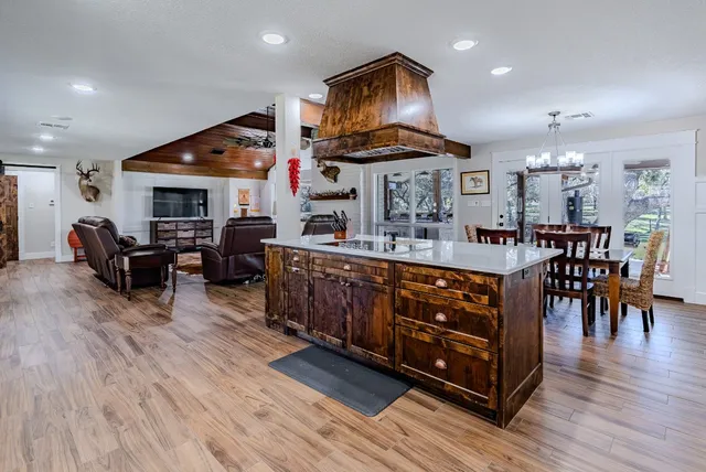 a living room with stainless steel appliances kitchen island a table and chairs in it