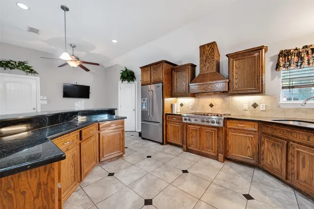 a kitchen with stainless steel appliances granite countertop a sink a stove and a refrigerator