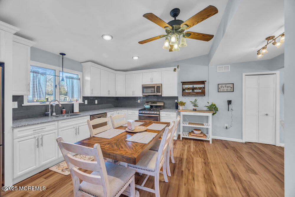 7 Maple Lane Howell, NJ 07731 - Photo 10 of 32 a kitchen with stainless steel appliances a stove a refrigerator a sink dishwasher a dining table and chairs with wooden floor