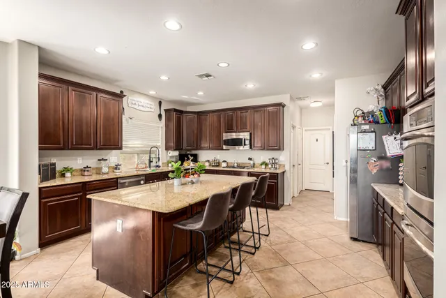 a kitchen with stainless steel appliances granite countertop a stove top oven a sink and a refrigerator