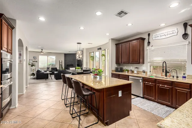 a kitchen with stainless steel appliances a sink a stove a refrigerator cabinets and living room view