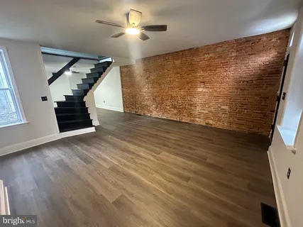 a view of an empty room with wooden floor a ceiling fan and windows