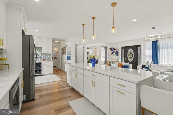 a kitchen with stainless steel appliances granite countertop a refrigerator a sink a stove and chairs with wooden floor