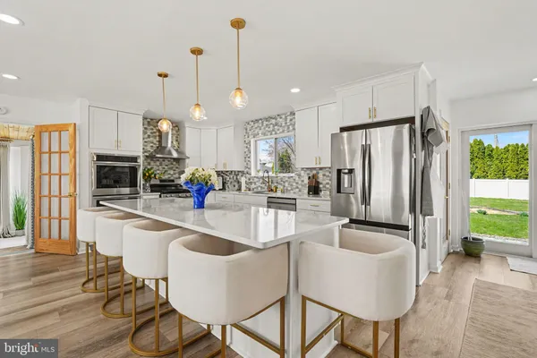 a large white kitchen with stainless steel appliances granite countertop a stove a sink and white cabinets