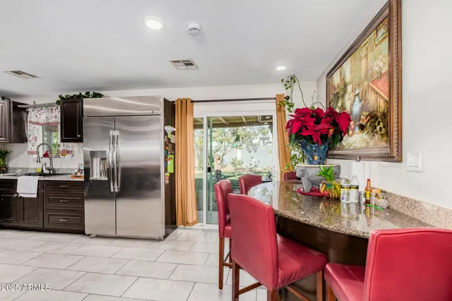 a kitchen with granite countertop a refrigerator dining table and chairs