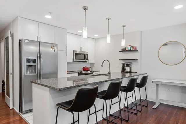 a kitchen with stainless steel appliances a dining table chairs refrigerator and microwave